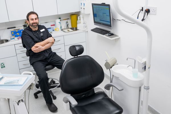 A male dentist sitting in his dental treatment room